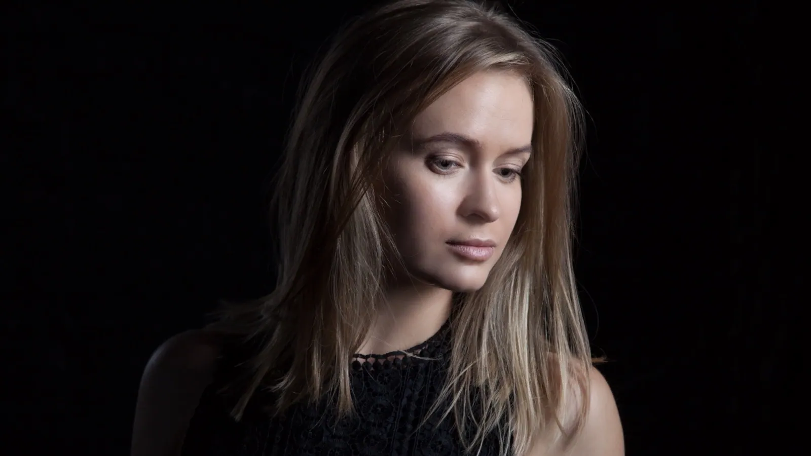 Krystyna in low-key studio light, eyes lowered