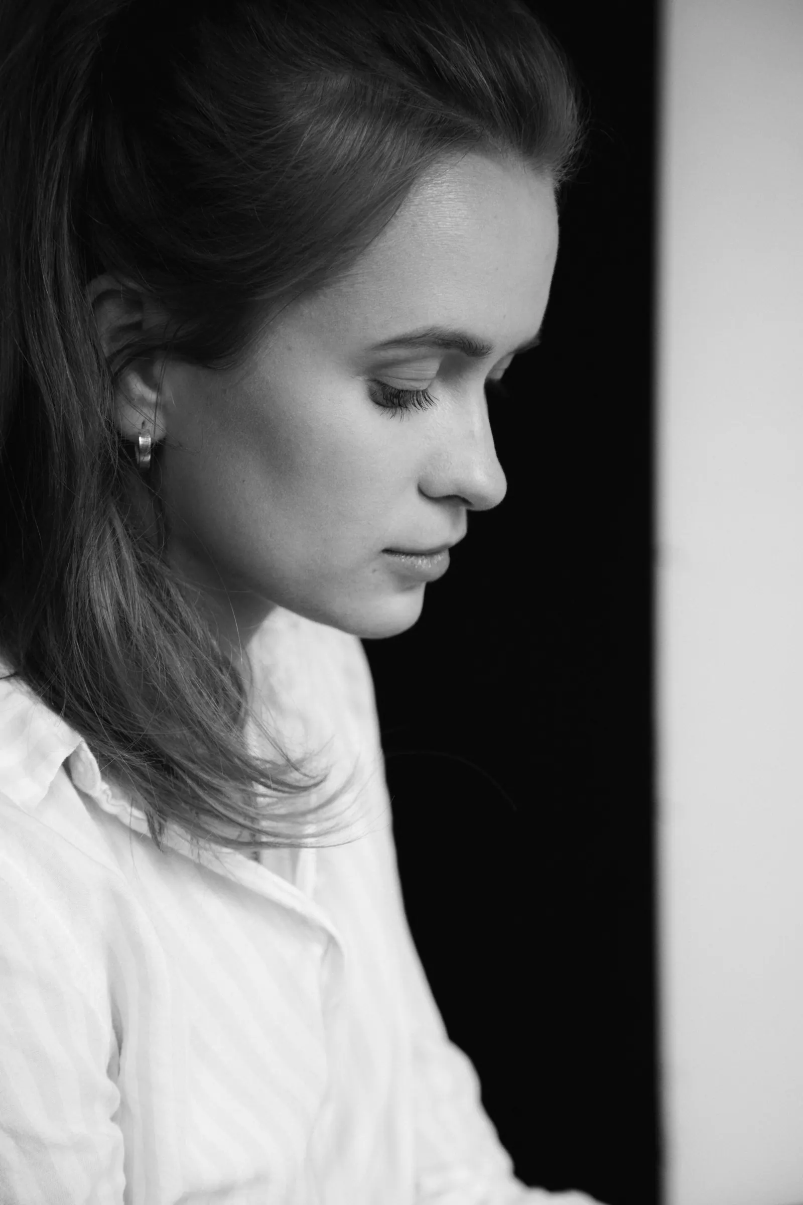 Black and white portrait of Krystyna in a white shirt, looking down